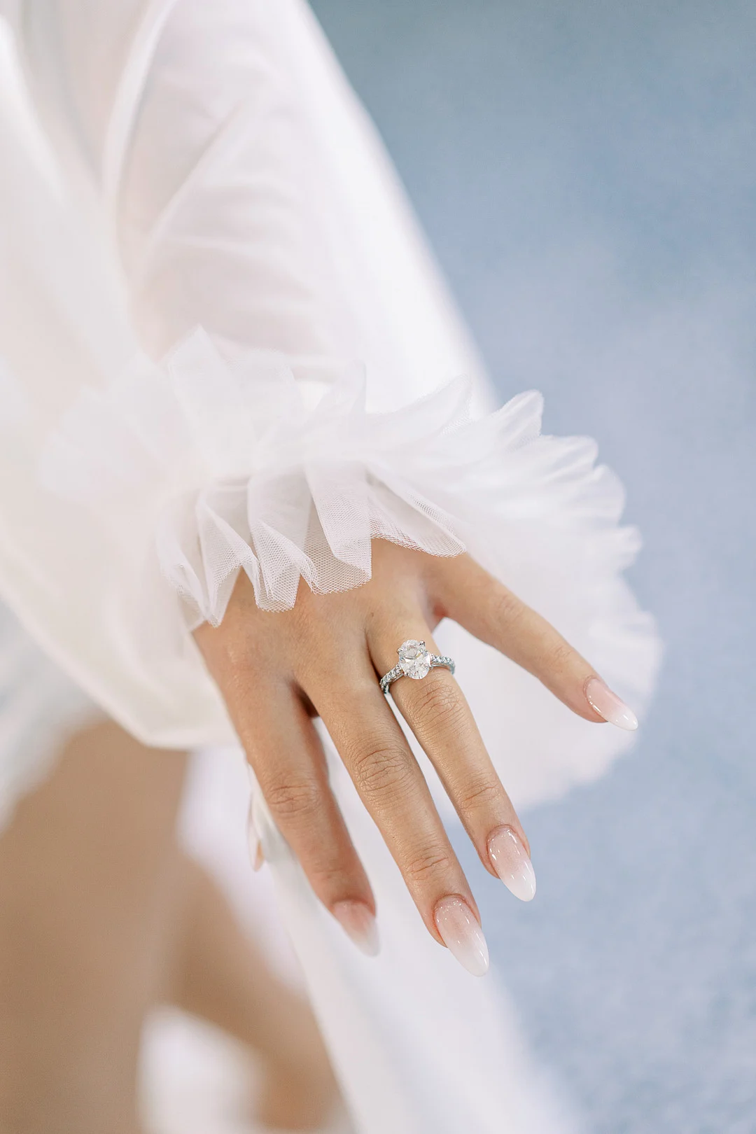 Détail de manche à plumes et bague de fiançailles ovale