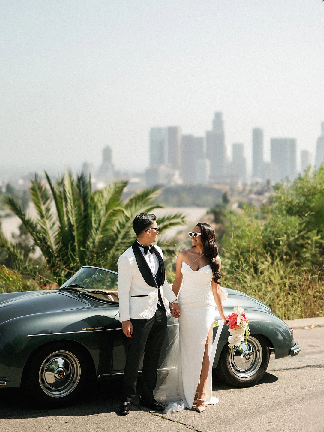 Un mariage glamour sur le toit de Los Angeles avec une Porsche vintage image 15 | Soirée Blanche Le couple debout près de la Porsche avec l'horizon complet du centre-ville