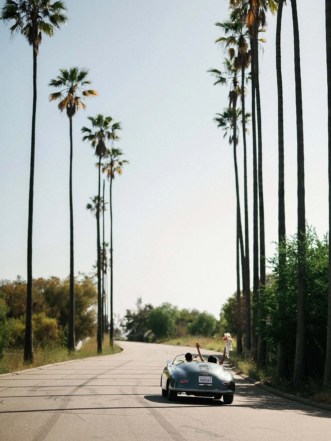 Un mariage glamour sur le toit de Los Angeles avec une Porsche vintage image 23 | Soirée Blanche Dyeneka et Kevin s'en vont dans une rue bordée de palmiers