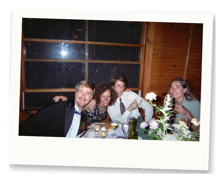 Invités de mariage à une table de réception des années 1990 avec une seule pièce maîtresse florale