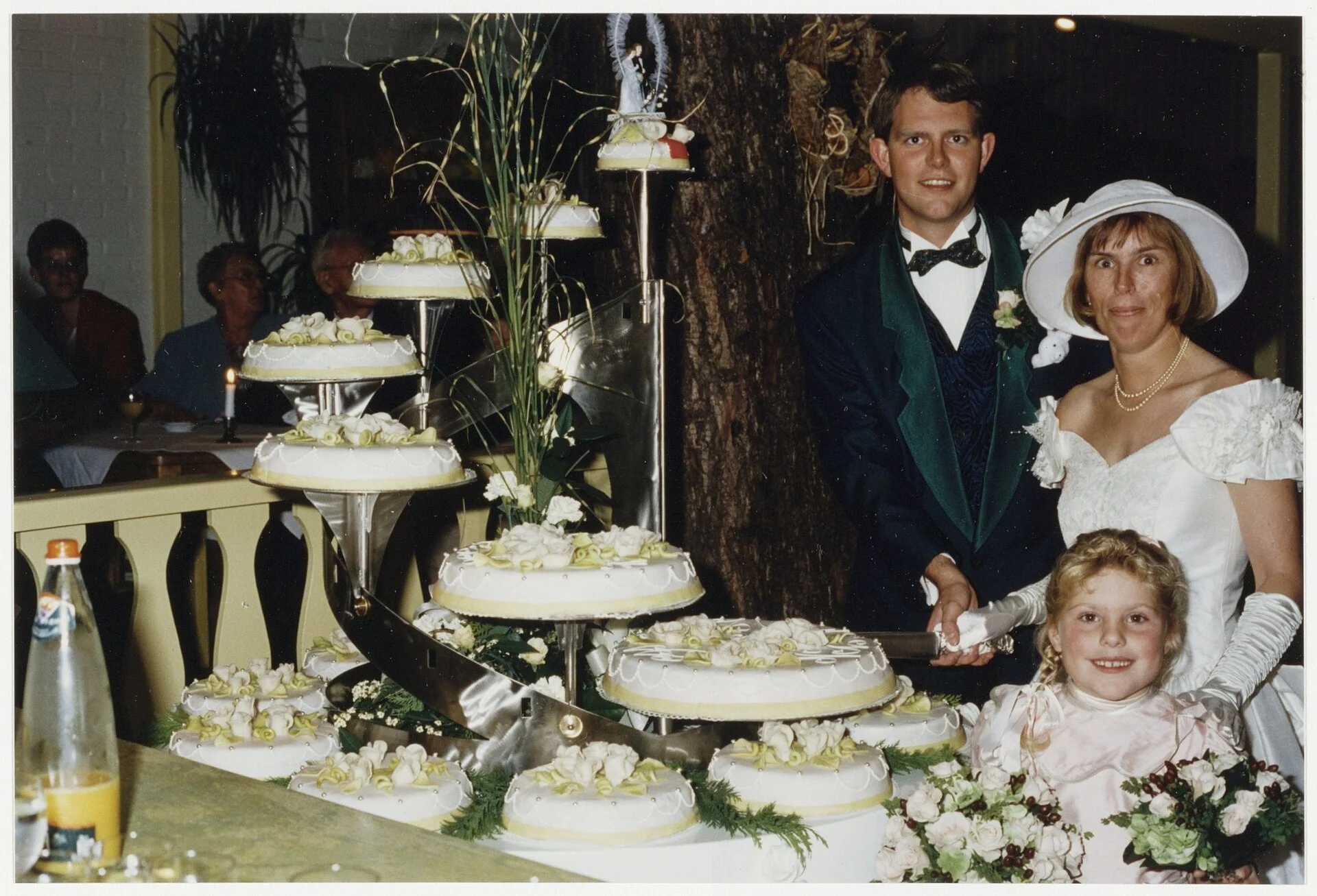 Les mariés coupent un imposant gâteau de mariage composé de nombreux petits gâteaux satellites disposés sur un support d'escalier en colimaçon chromé, 1994