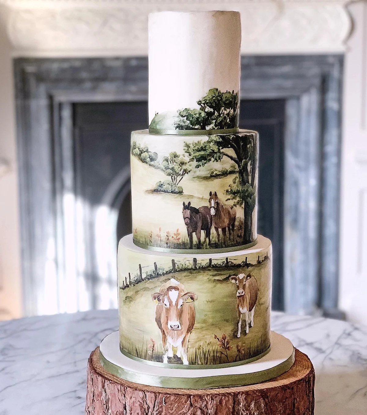 Gâteau de mariage à trois niveaux peint à la main avec des vaches et des chevaux paissant dans un pâturage