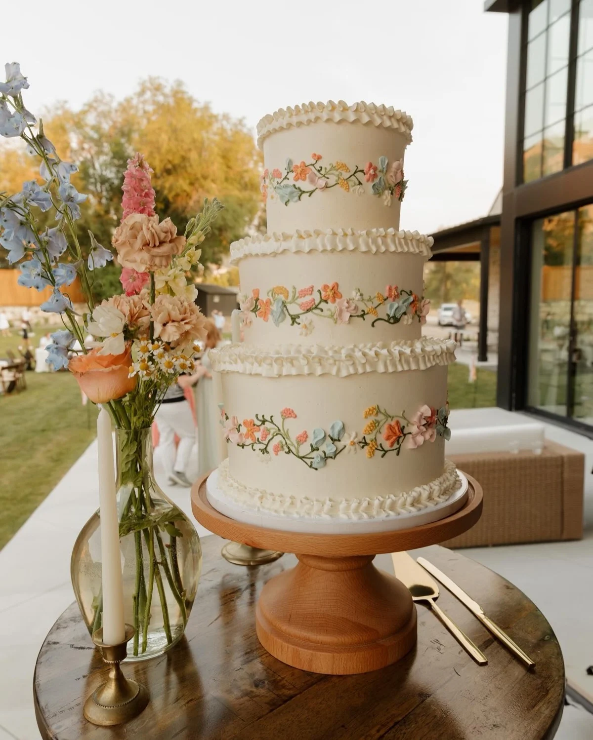 Gâteau de mariage passepoilé vintage avec des guirlandes de fleurs sauvages passepoilées à la main enveloppant chaque niveau