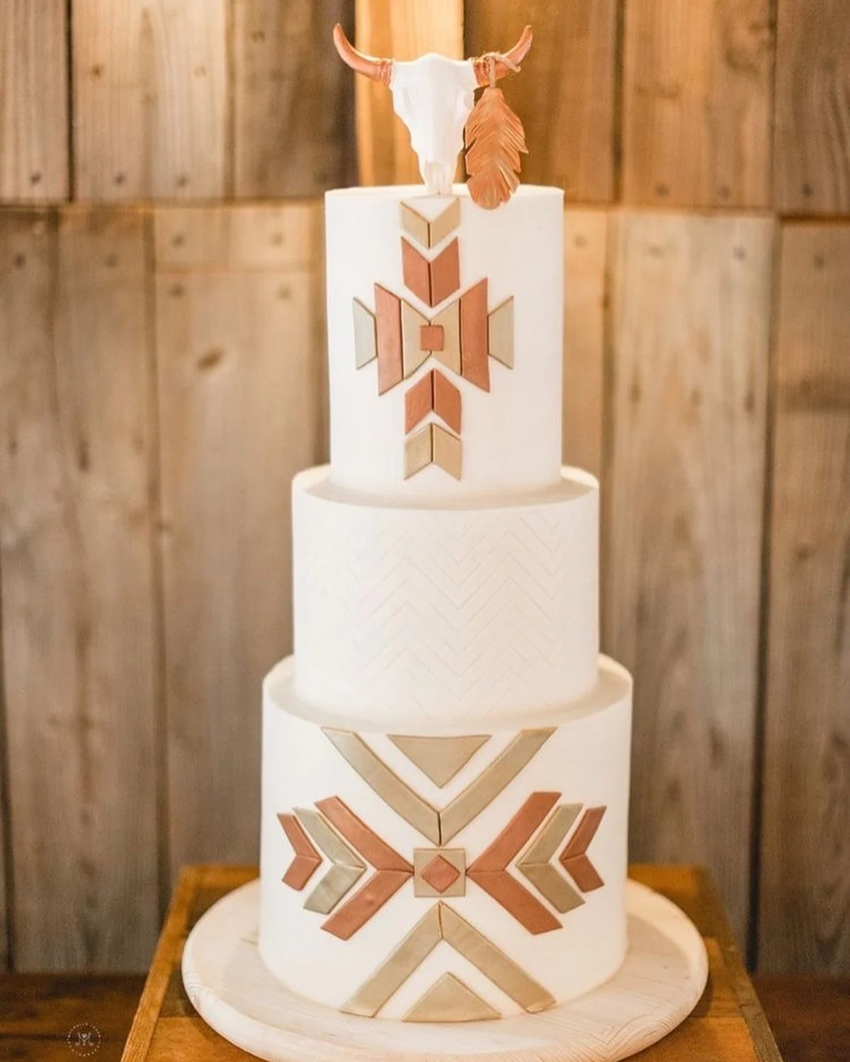 Gâteau de mariage avec un crâne de vache blanc, une plume en cuivre et des motifs de carreaux du sud-ouest