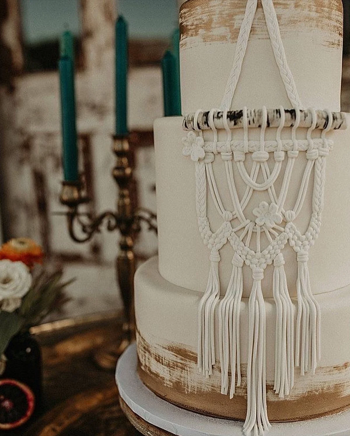 Gâteau de mariage avec un macramé passepoilé sur le devant et des étages en or brossé