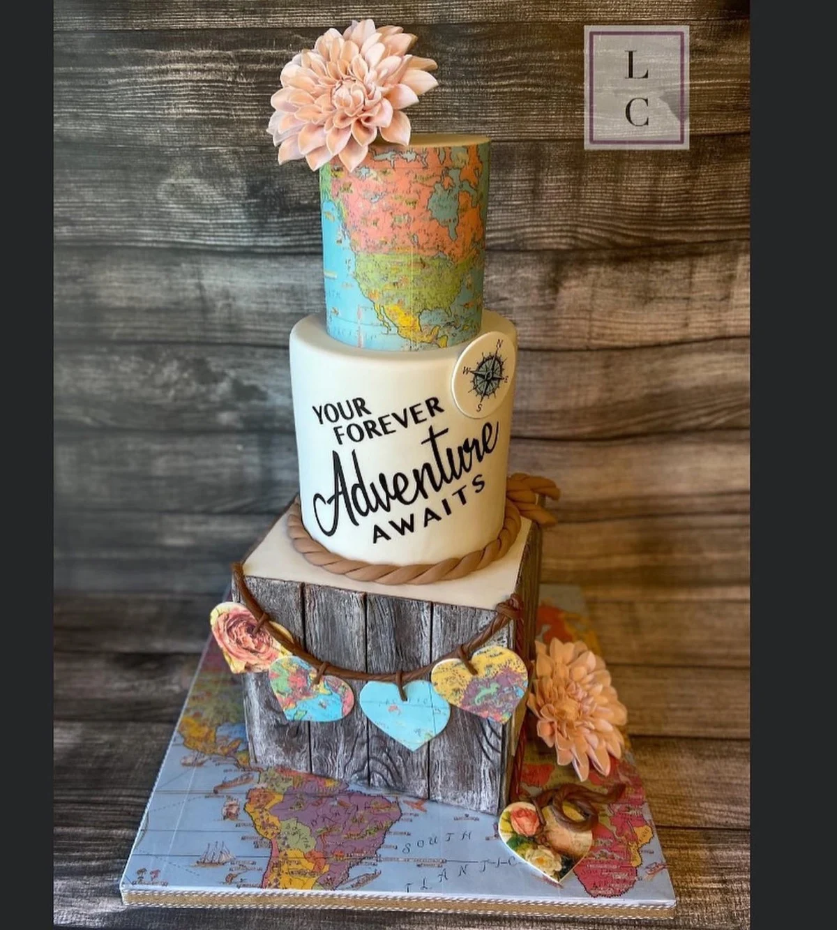 Gâteau de mariage sur le thème de l'aventure avec des niveaux de carte, un niveau de grain de bois et le script Your Forever Adventure Awaits