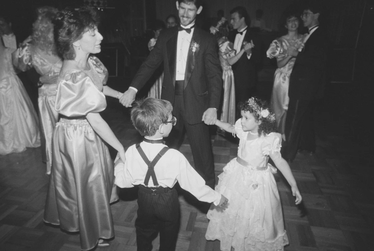 La noce dansant en cercle avec le porteur de l'anneau et la bouquetière lors d'une réception en 1989