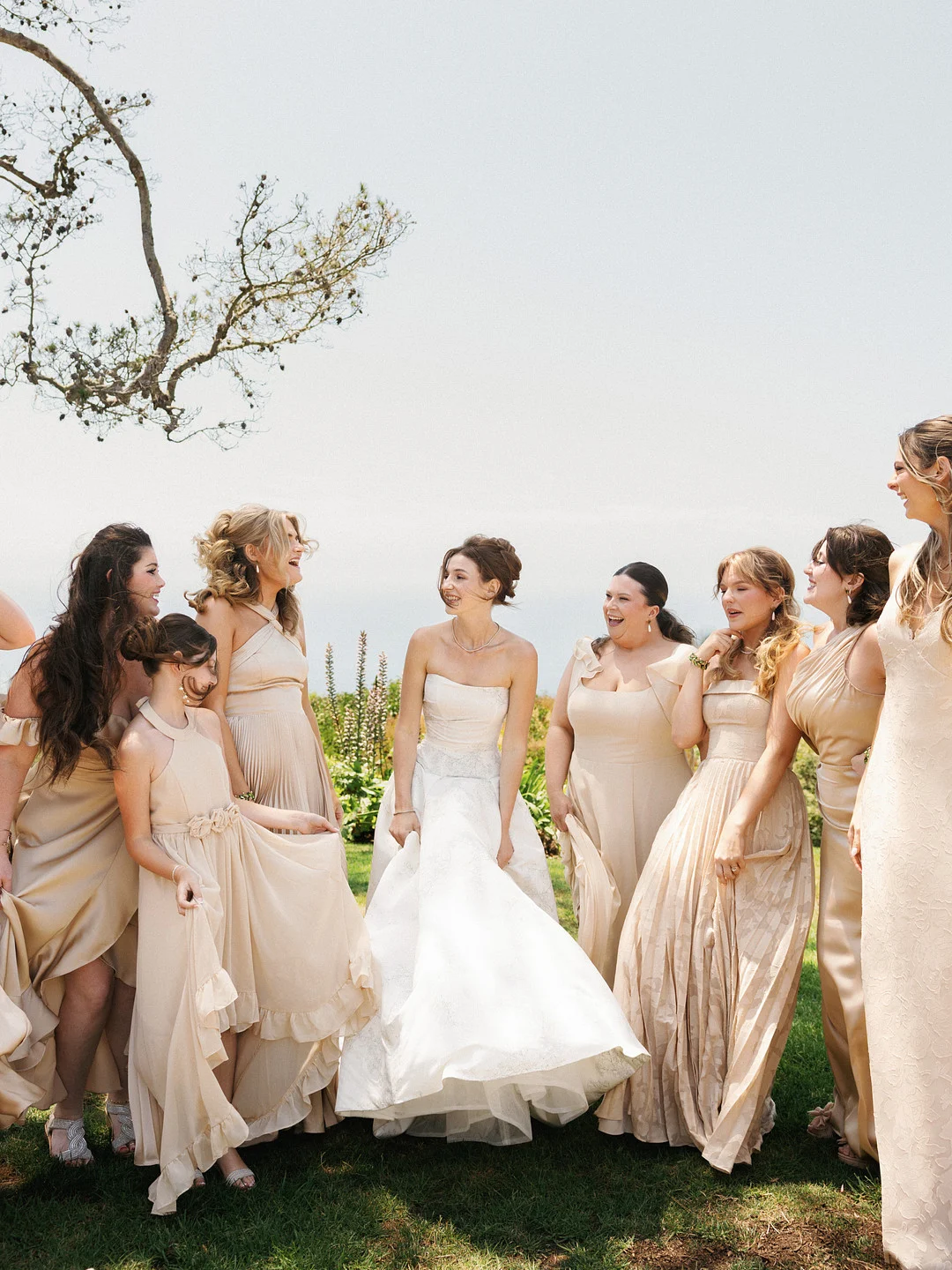 Baylee rit avec ses demoiselles d'honneur vêtues de robes champagne sur la pelouse