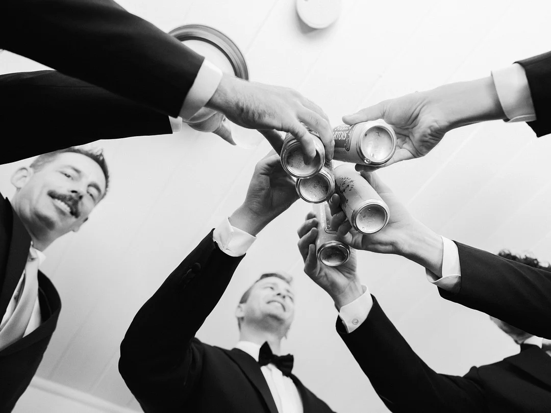 Photo aérienne en noir et blanc d'Avery et de ses garçons d'honneur trinquant avec des bières