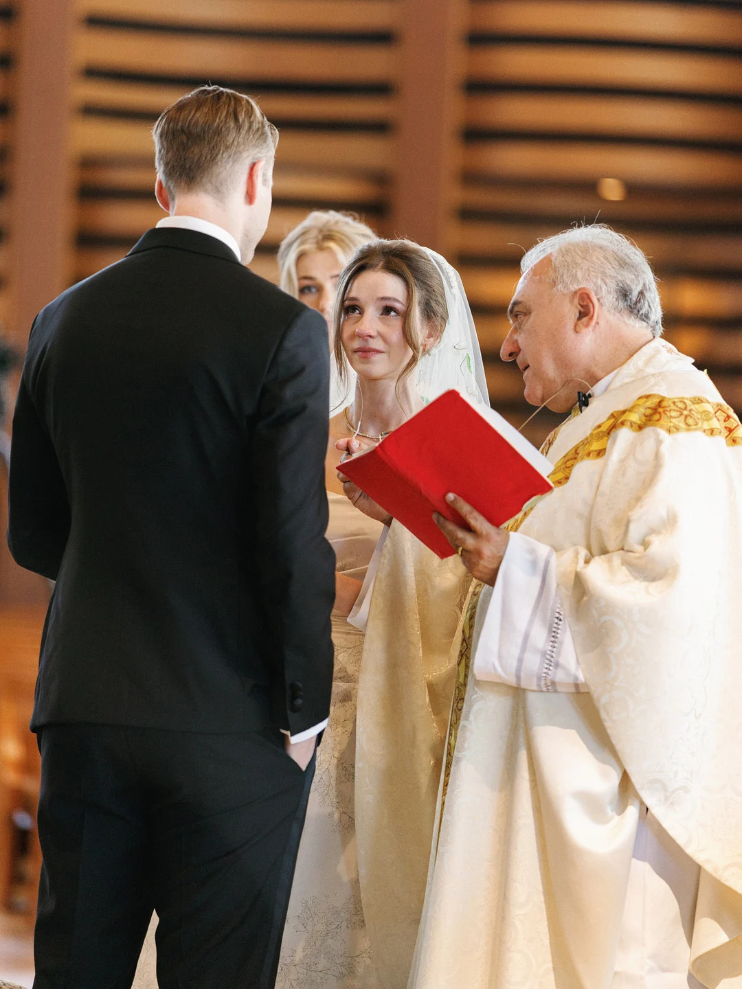 Baylee regarde Avery pendant que le prêtre lit pendant leur cérémonie de mariage catholique